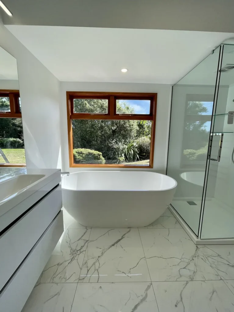 Same bathroom after renovation with freestanding bath and marble look tiles