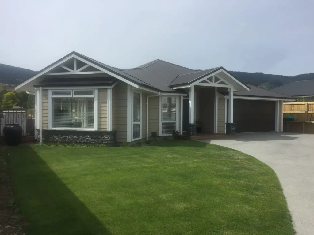 Grey weatherboard new home with gabled entrance and double garage